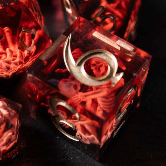 Blood-red resin dice set Crimson Reliquary – handmade polyhedral dice with skeleton fragments inside.